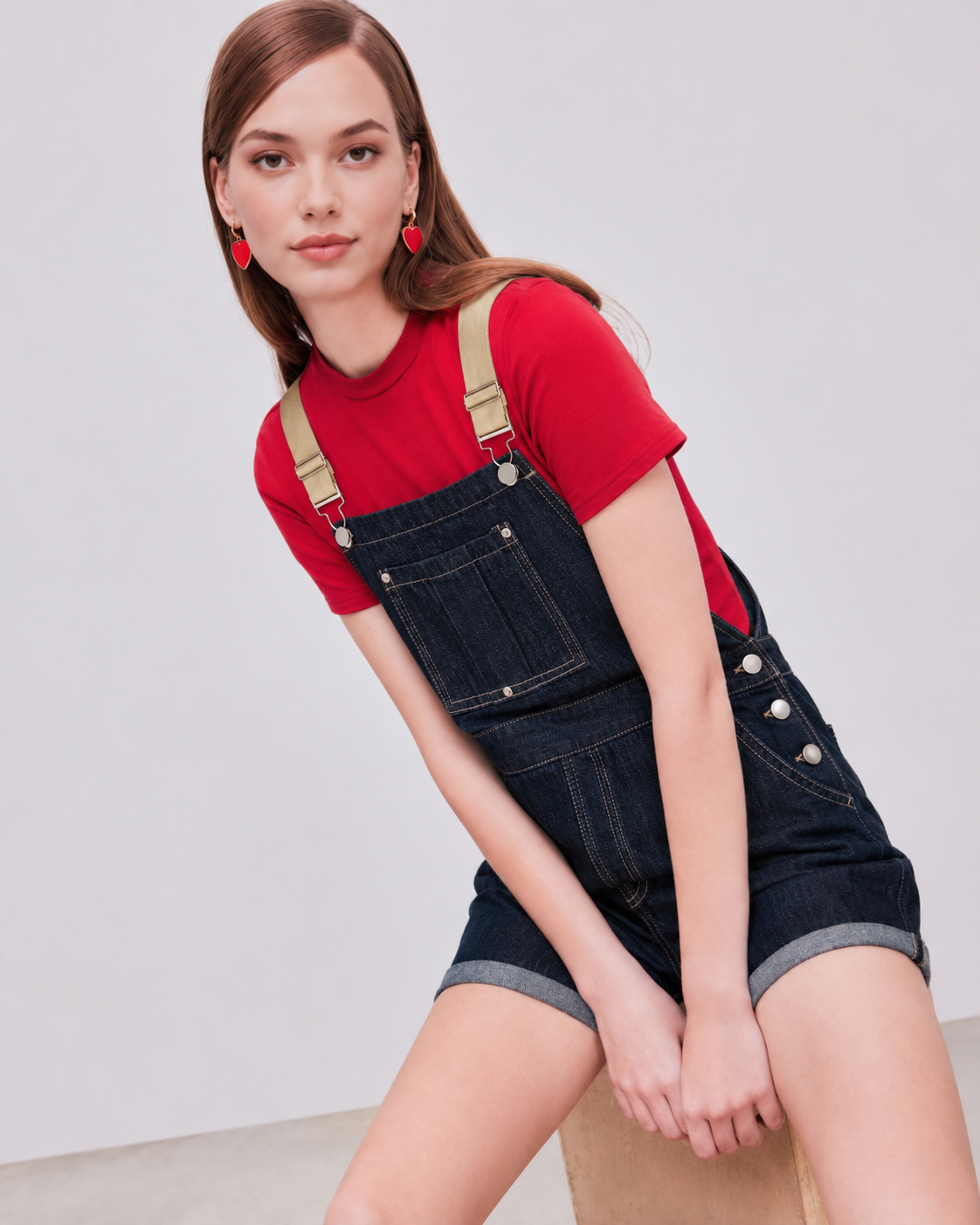 Denim relaxed overall romper on model, seated three-quarter view