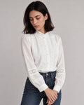 White lace-trim stand-collar blouse tucked into dark jeans, with hands resting below the waist.