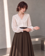 Workday Edit Look 01 – White lace-trim V-neck blouse 3244, upper-body cuff interaction with Coffee Brown pleated midi skirt 8252 in the gray wall scene.